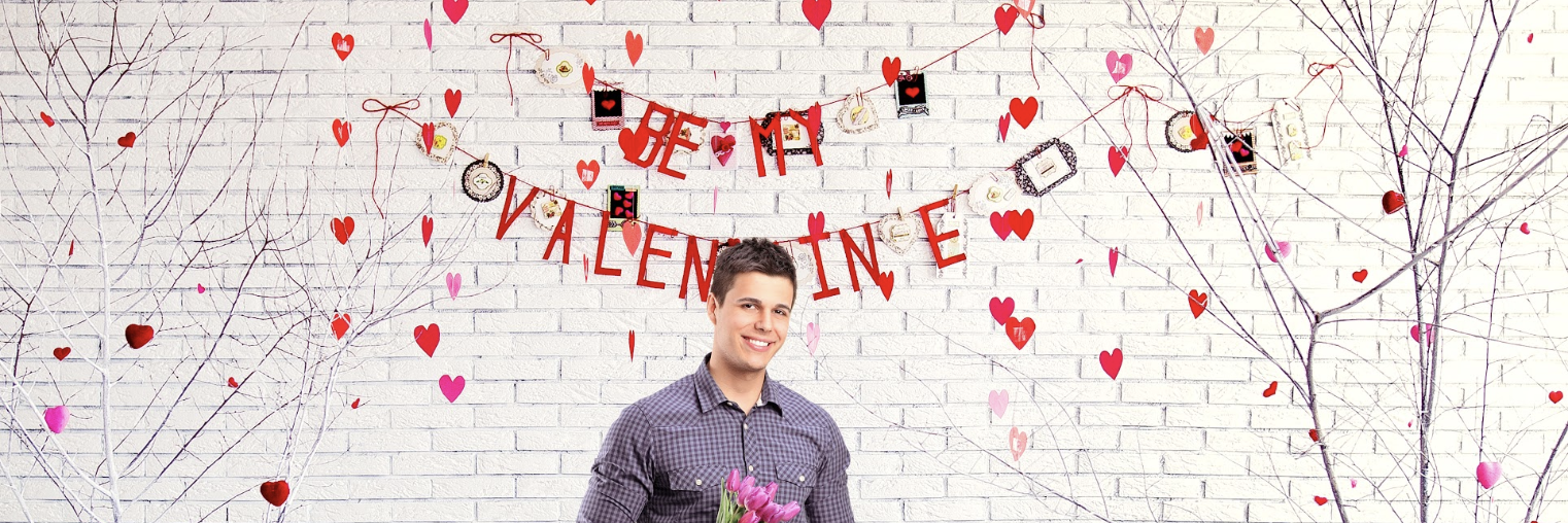 Image of a man holding flowers in front of a sign that says "Be My Valentine" - the best valentines day image. 